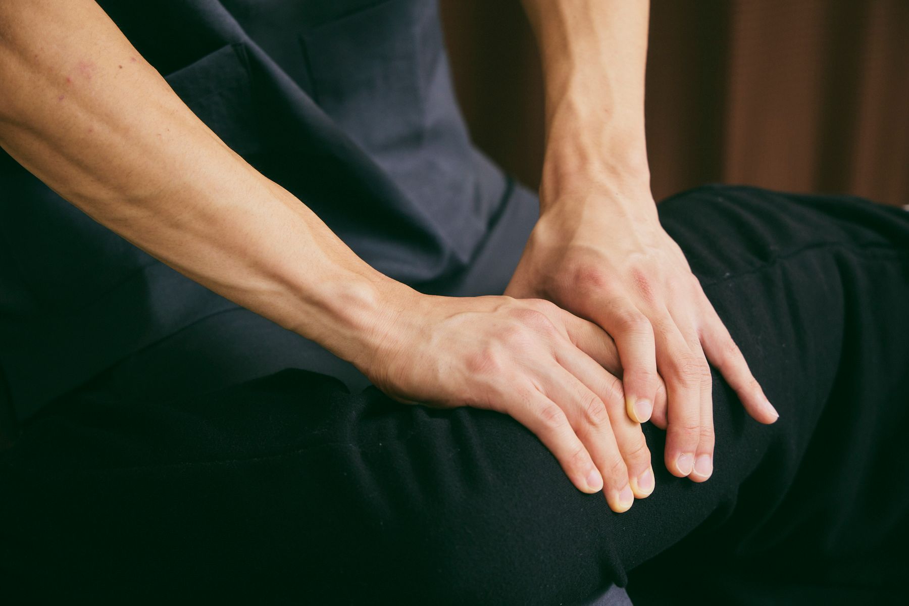 理学療法士の両手が、脚に触れて体の状態を確かめている手元
