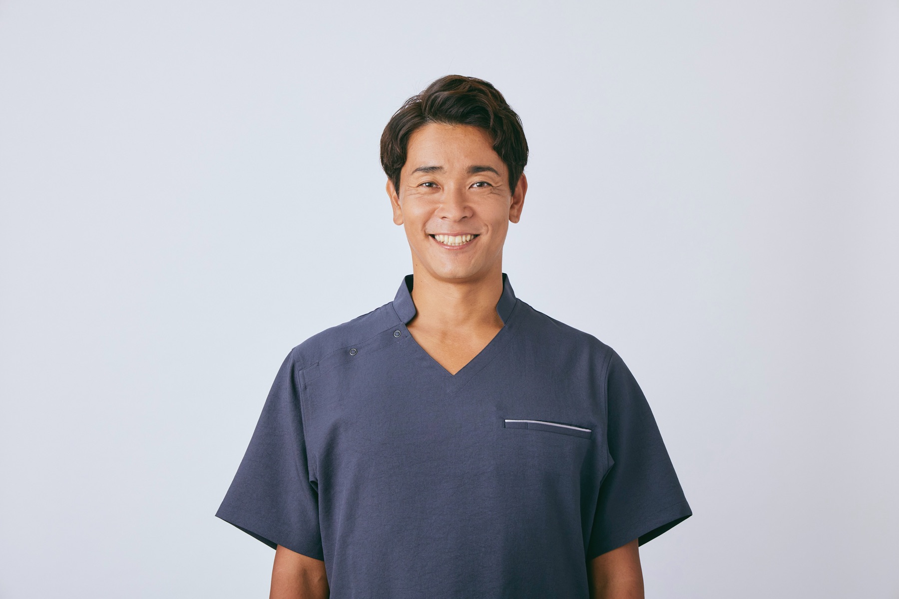 紺のスクラブを着て笑顔で正面を向く、理学療法士・氏原大貴